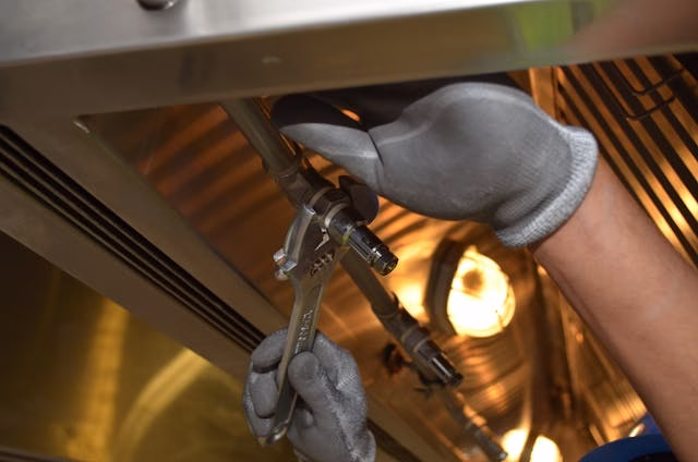 Plumber who has done a Camera Inspection and found the problem in a pipe that he is opening up while wearing grey gloves.